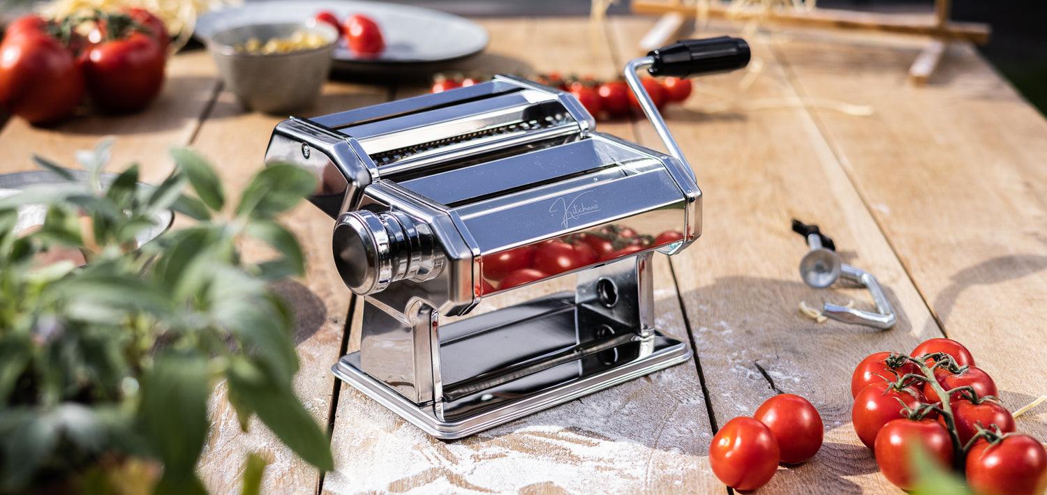 Een functionele weergave van de zilverkleurige Kitchenz pastamachine, stevig gemonteerd op een werkblad, klaar om vers pastadeeg om te toveren tot perfecte lasagnebladen of tagliatelle.  
Kitchenz pastawals, handmatige deegmachine, rvs pastasnijder, Kitchenz keukenapparaat, universele pastamaker, zelf pasta maken tool, instelbare dikte pastamachine.