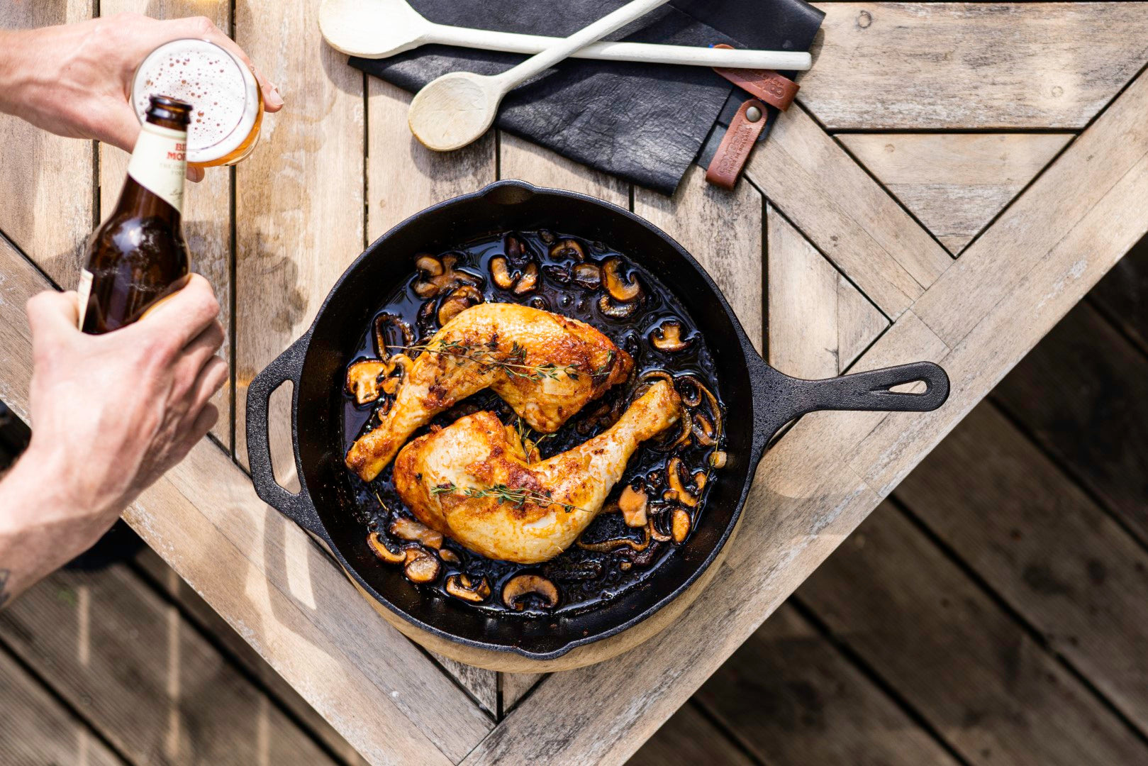 Een luxe buitenkeuken met een Kitchenz gietijzeren skillet op een houten werkblad, klaar voor een zomerse BBQ avond met vrienden. buitenkeuken accessoires, Kitchenz skillet lifestyle, luxe barbecue pan, gietijzeren koekenpan buiten, zomerse BBQ sfeer, professioneel buitenkoken.